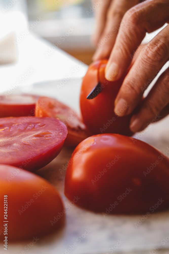 Cropped hands of woman cutting tomatoes on table in kitchen Cropped hands of woman cutting tomatoes on table in kitchen