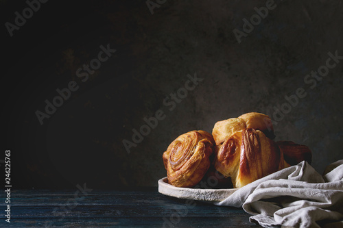 Photo Variety of homemade puff pastry buns cinnamon rolls and croissant in ceramic plate on wooden table
