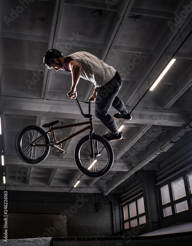 Canvas Print Young BMX making crazy tricks on his bicycle in skatepark indoors