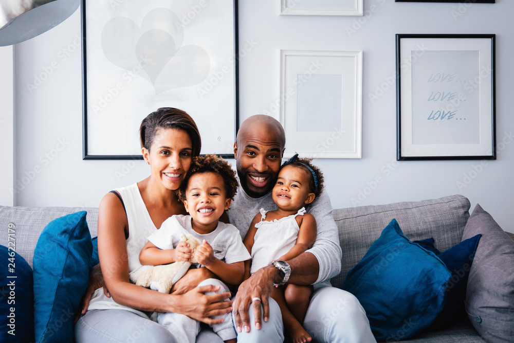 Portrait of smiling parents with cute children sitting on sofa at home