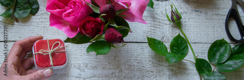 Top view of female decorator holding a  gift box, arranging roses on the wooden table, Concepts - fiorist, occupation, hobby, small business photo