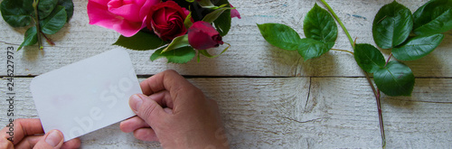 Top view of female decorator holding a  card, arranging roses on the wooden table, Concepts - fiorist, occupation, hobby, small business photo