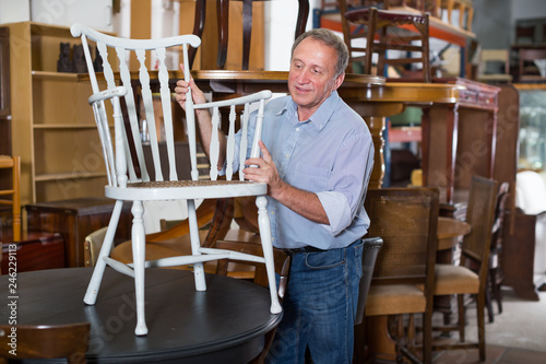 Man with wife are choosing old antique chair in shop