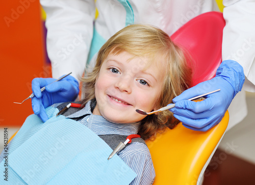 smiling child with light curly hair on examination in the dental chair