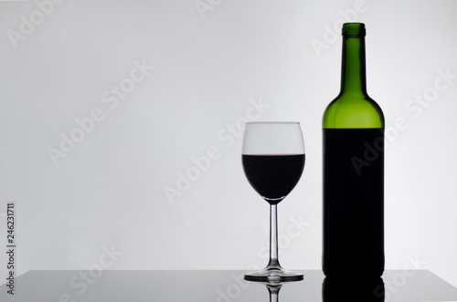 Wine bottle and wine glass on black glossy table white background