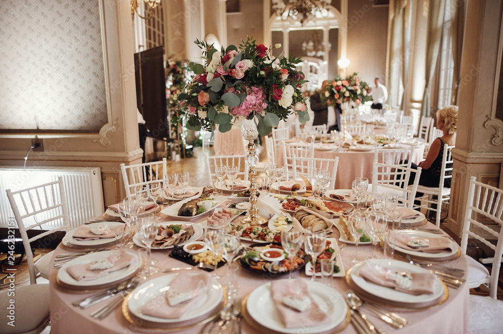 Wedding dinner table setting. Pink flowers and decor details on festive served tables