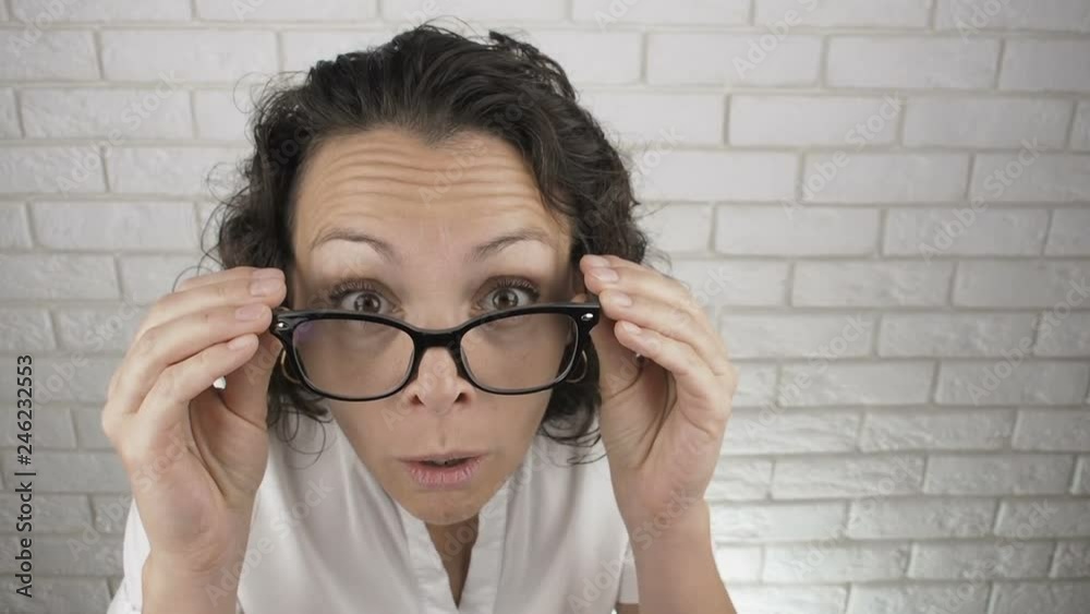 Shocked woman looking out of glasses. Surprised woman takes off her glasses. Shocked woman looking out of glasses. Surprised woman takes off her glasses.