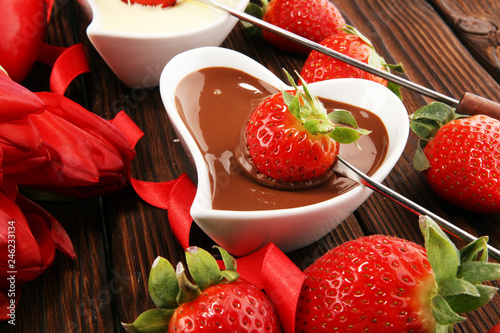 Valentine Chocolate fondue melted with fresh strawberries and dark and white chocolate. Tublips and sugar hearts. photo