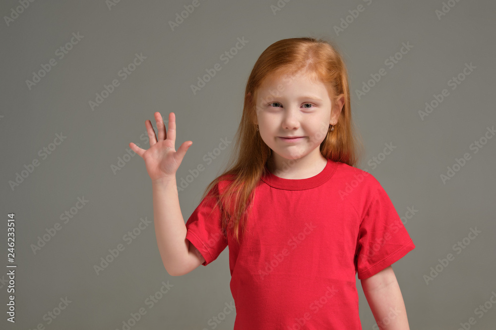 A little girl shows gesture - five fingers, isolated on grey background A little girl shows gesture - five fingers, isolated on grey background
