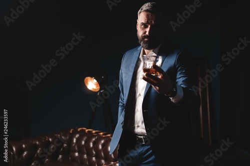 Degustation, tasting. Man with beard holds glass of brandy. Tasting and degustation concept. Bearded businessman in elegant suit with glass of whiskey