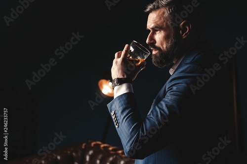 Degustation, tasting. Man with beard holds glass of brandy. Tasting and degustation concept. Bearded businessman in elegant suit with glass of whiskey photo
