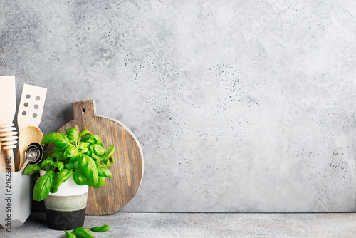 Kitchen shelf. Appliances for the kitchen in a gray modern stand, basil in a gray mug on the background of a gray concrete wall. Horizontal, space.