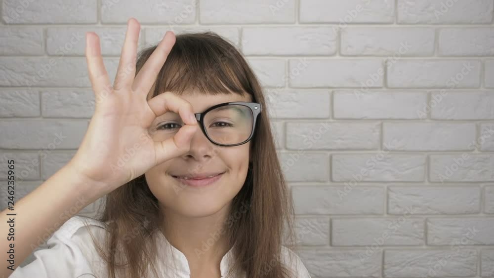 Child with glasses shows OK gesture. Happy little girl in glasses for sight shows a sign ok. Child with glasses shows OK gesture. Happy little girl in glasses for sight shows a sign ok.