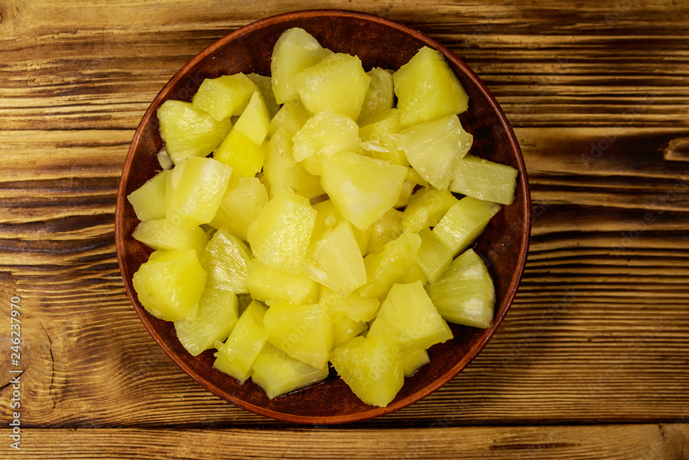 Canned pineapple pieces in ceramic plate on wooden table Canned pineapple pieces in ceramic plate on wooden table