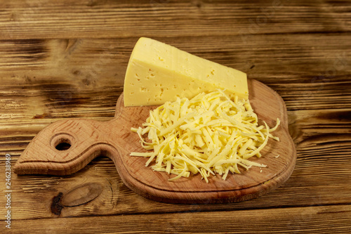 Grated cheese on cutting board on wooden table