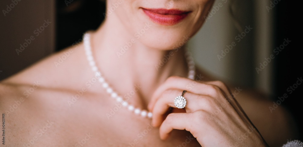 Woman touches tender pearl necklace on her neck