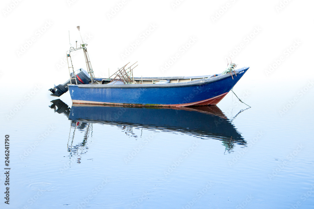 Barco azul de pesca parado reflete a sua imagem na água