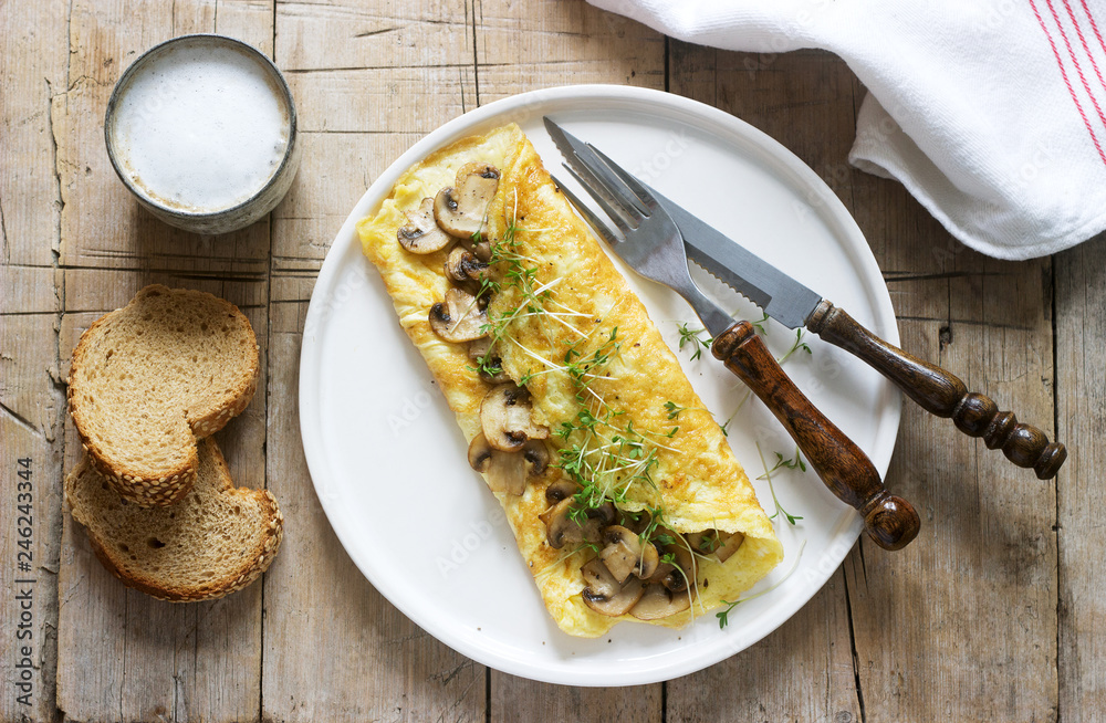 Vegetarian breakfast, omelette with mushrooms and cress, served with rye bread and coffee with milk. Rustic style.