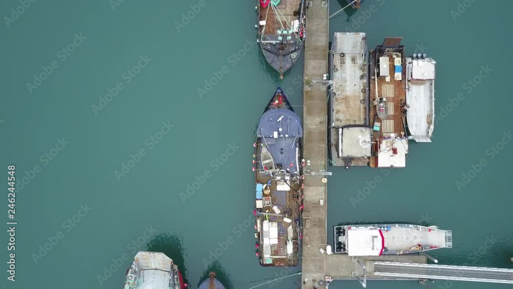 Aerial birds eye view flying over large commercial ships docked in the harbor in Homer, Alaska