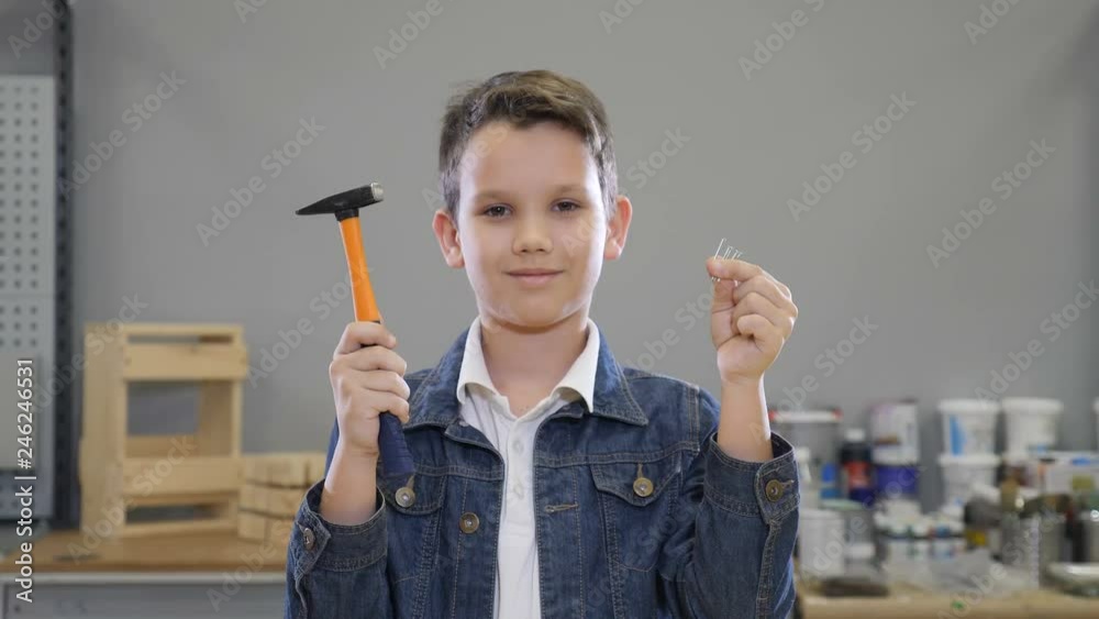 Boy and building implements with Hammer and nails in hands closing and opening eyes smiling. Handcraft concept. hobby and leisure time at locksmiths workshop. 4k