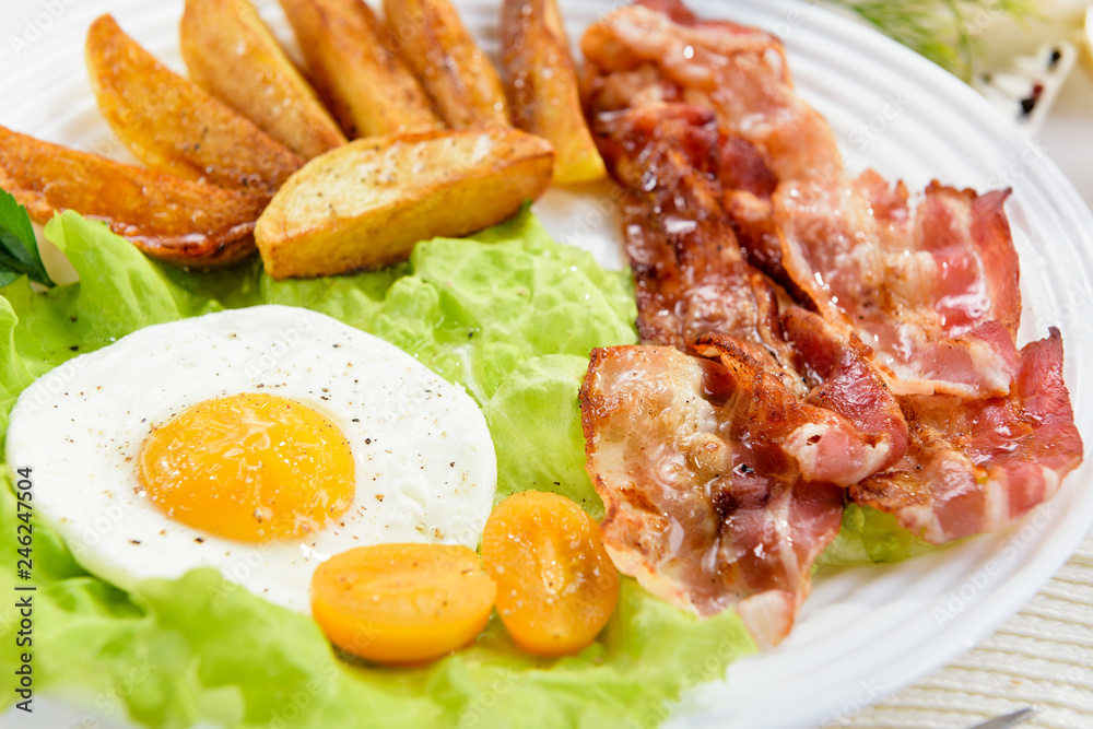Fried bacon with French fries and a delicate egg, close-up. Fried bacon with French fries and a delicate egg, close-up.