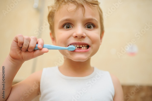 close up photo of a blond boy cleaning his teeth in a bathroom
