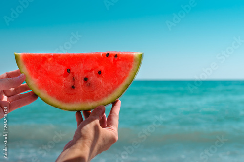 Watermelon, juicy slice in the hands of a woman with over the sea. Diet of tropical fruits.