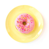 Pink Iced donut on a colourful plate with sprinkles