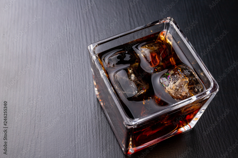 A cold drink with ice on a dark table. A chilled drink in a glass. A cold drink with ice on a dark table. A chilled drink in a glass.