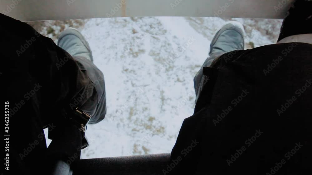 POV shot: a happy skier climbing or descending a mountain on a skilift, looking down at the snowy land moving right under his feet. POV shot: a happy skier climbing or descending a mountain on a skilift, looking down at the snowy land moving right under his feet.