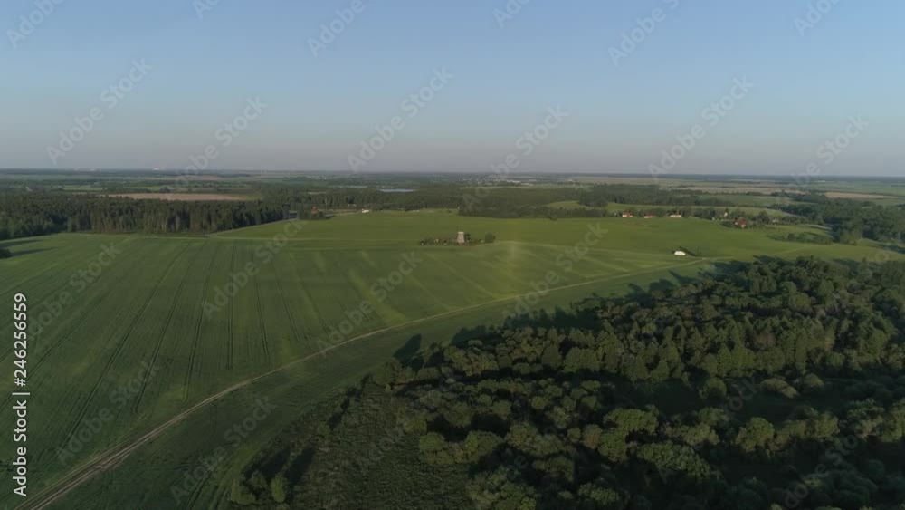 Aerial flying flies over Dududki located around a forest and cultivated fields in sunny summer weather. Aerial flying flies over Dududki located around a forest and cultivated fields in sunny summer weather.