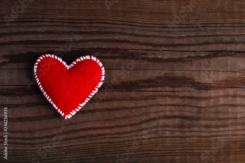 Red heart made of felt on a wooden table. Handmade blank for greeting card, copy space.