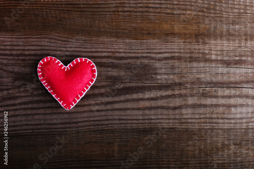 Pink heart made of felt on a wooden table. Handmade blank for greeting card, copy space.
