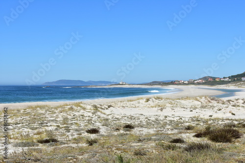 Beach with vegetation in sand dunes and lighthouse. Playa de Lariño, Carnota, Coruña Province, Spain.