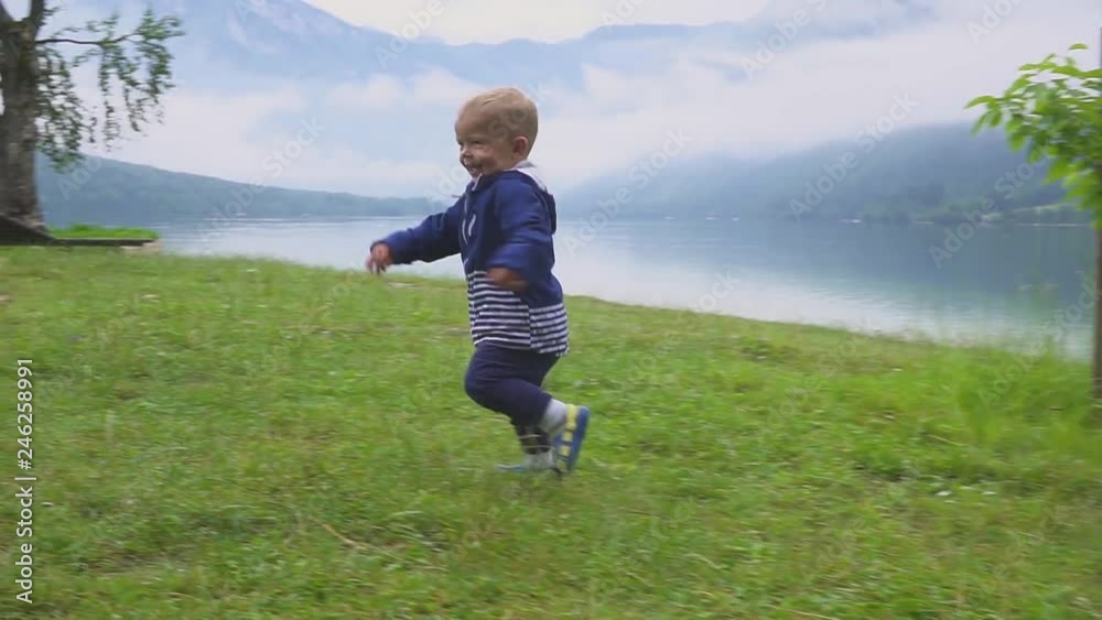 the little boy walks near the mountain lake. Running and frolicking in nature. the little boy walks near the mountain lake. Running and frolicking in nature.