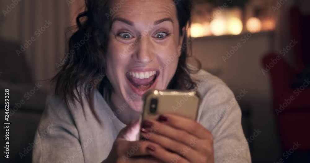 Excited young woman enjoying media content on mobile phone at night Excited young woman enjoying media content on mobile phone at night