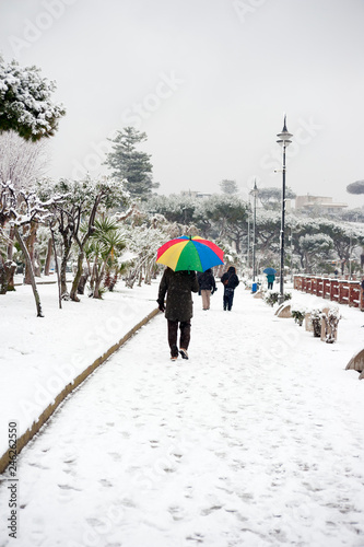 man with colorful umbrella in snowy park.