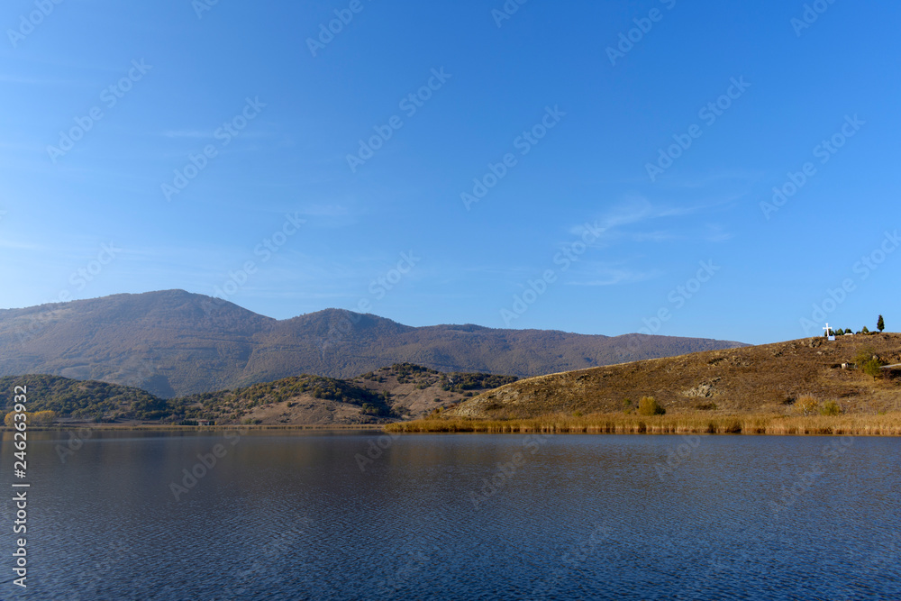 Lake Zazari with a background of the mountains, greek flag and the big cross