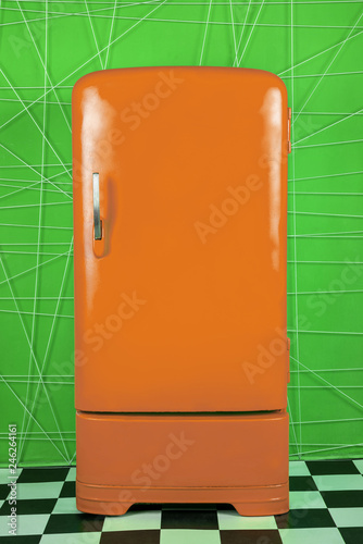 old vintage orange refrigerator on a green background