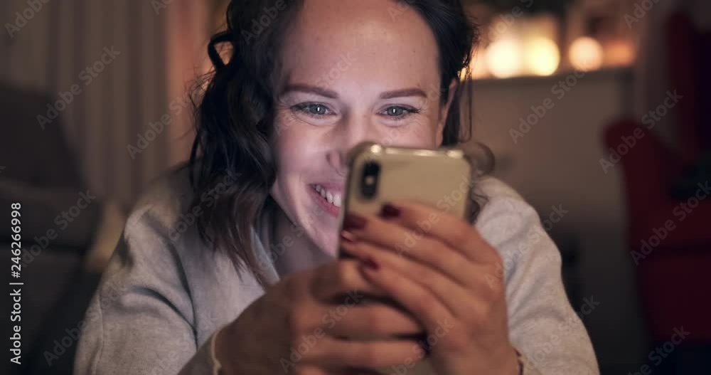 Excited young woman playing game on mobile phone at night