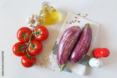 Raw graffiti eggplants, garlic, tomatoes  on light background