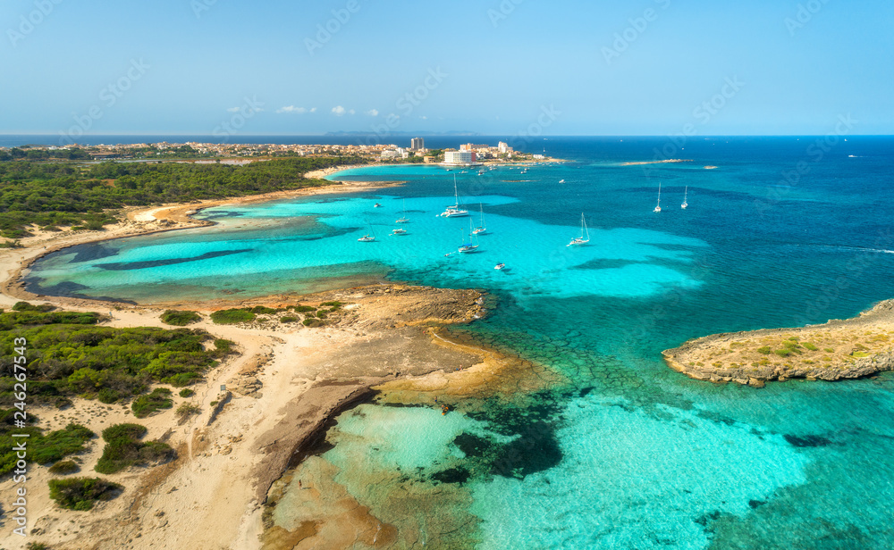 Aerial view of beautiful sea with transparent azure water, rocks, sandy beach, green trees, boats and luxury yachts at sunny day in summer. Mallorca, Spain. Colorful seascape. Top view from drone