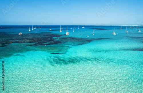 Aerial view of boats and luxury yachts in transparent sea at sunny bright day. Summer seascape. Tropical landscape with lagoon, boats, azure water, sandy beach, blue sky. Top view from drone. Travel