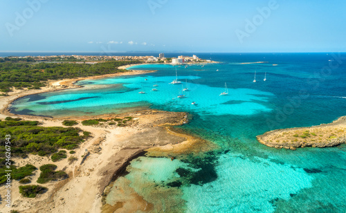 Aerial view of beautiful sea with transparent azure water, rocks, sandy beach, green trees, boats and luxury yachts at sunny day in summer. Mallorca, Spain. Colorful seascape. Top view from drone