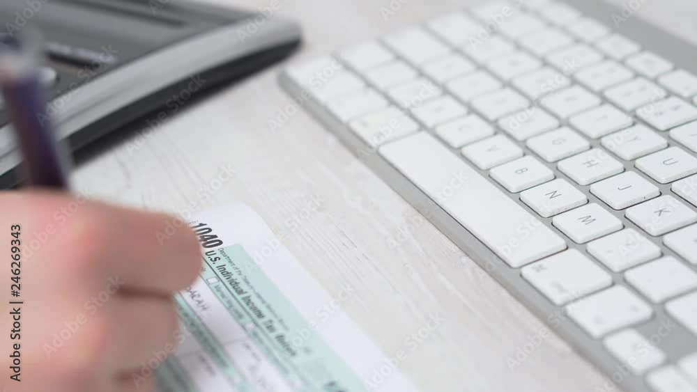 Closeup Slider movement of woman filling tax form 1040 on the desk next to computer keyboard and calculator. 4k video Closeup Slider movement of woman filling tax form 1040 on the desk next to computer keyboard and calculator. 4k video