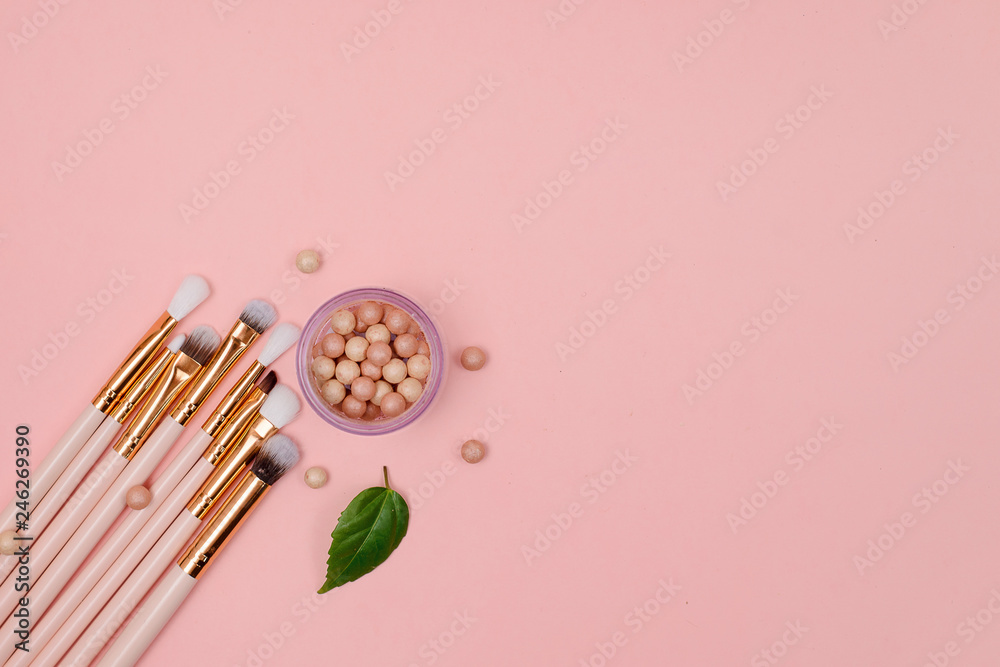 Cosmetics, makeup brushes and flowers on a pink background. Close-up. Top view. Cosmetics, makeup brushes and flowers on a pink background. Close-up. Top view.