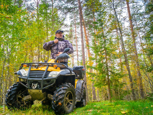 Travel without roads. ATV. A man rides through the forest on an all-terrain vehicle. Quad bike. In the woods. ATV trip to the forest © Grispb