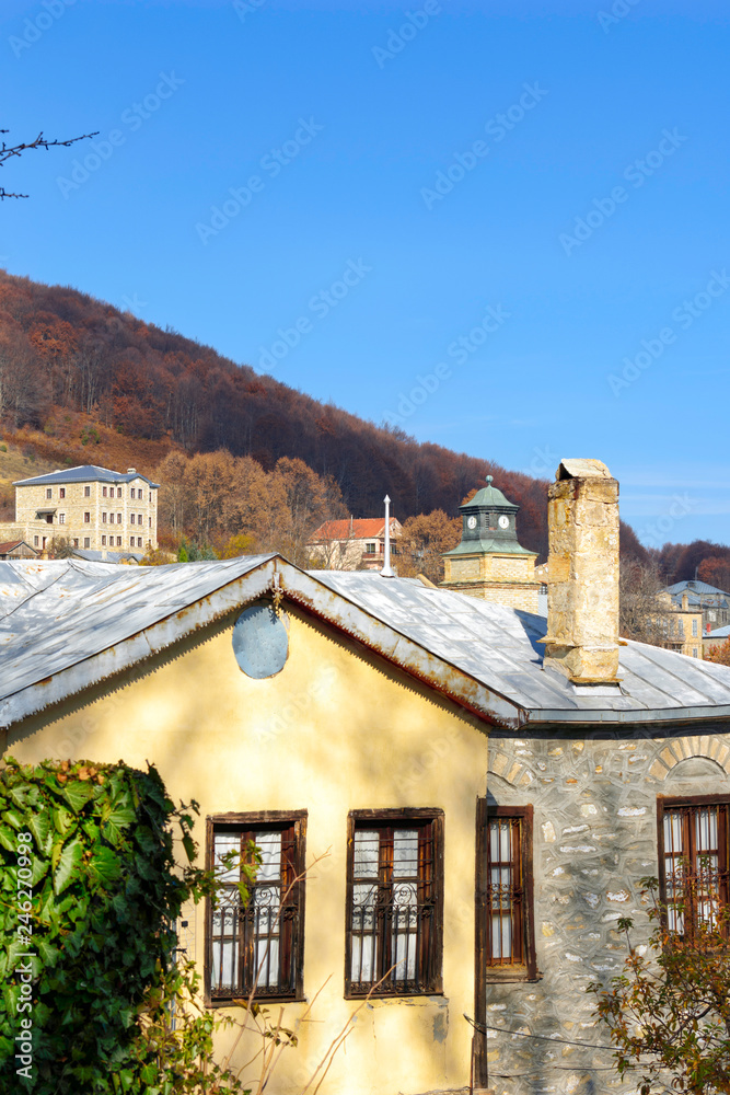 A traditional home with a tower clock background in the village of Nymfaio.