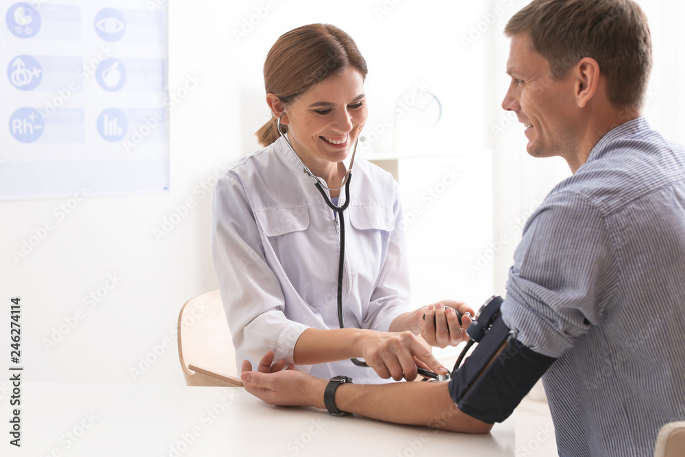 Doctor checking patient's blood pressure in hospital. Cardiology concept
