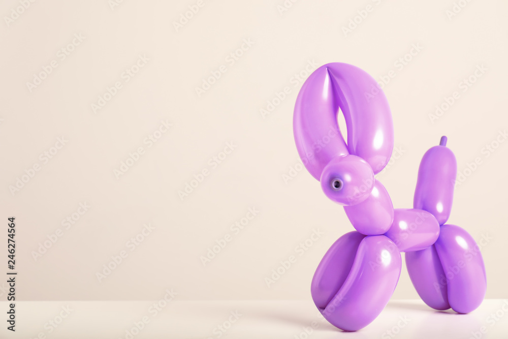 Animal figure made of modelling balloon on table against color background. Space for text Animal figure made of modelling balloon on table against color background. Space for text